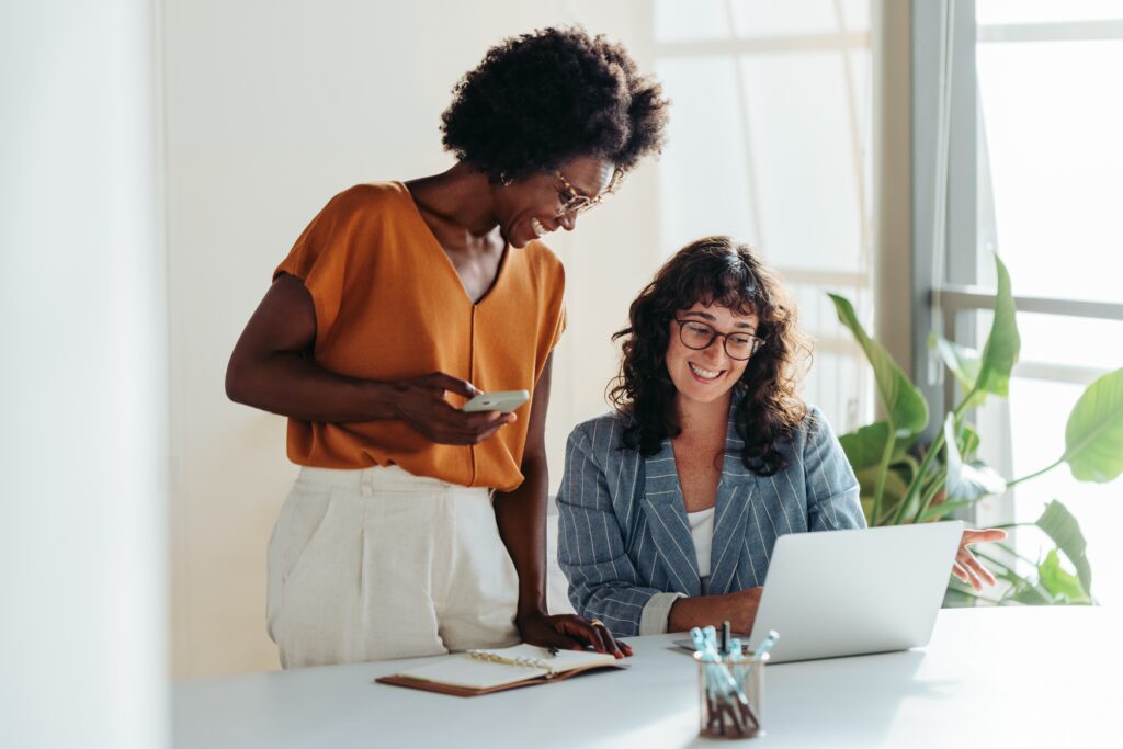 twee vrouwen achter de laptop glimlachend