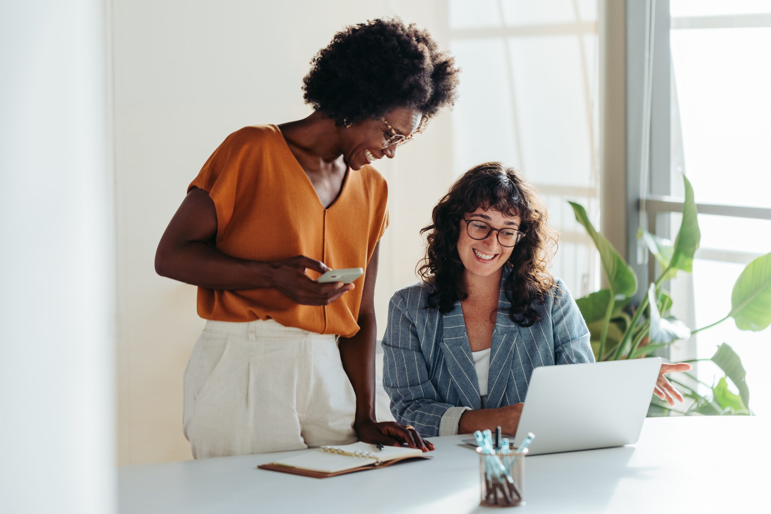 twee vrouwen achter de laptop glimlachend